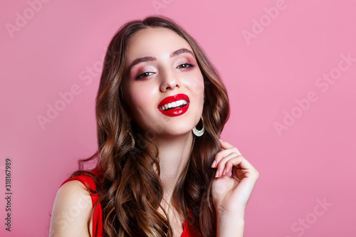 Close-up portrait of young beautiful girl.Perfect toothy smile. Red lips and perfect skin on pink background.