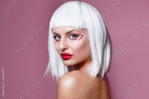 Beauty fashion model girl creative art makeup with red hearts and white hair on pink background
