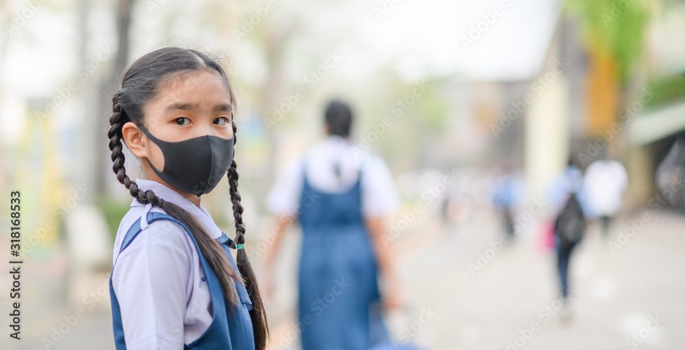 Portrait Asian children girl wear mask to protect PM 2.5 dust and air pollution. Portrait of Thai student wearing protection mask bad weather, pm2.5 concept background Portrait Asian children girl wear mask to protect PM 2.5 dust and air pollution. Portrait of Thai student wearing protection mask bad weather, pm2.5 concept background