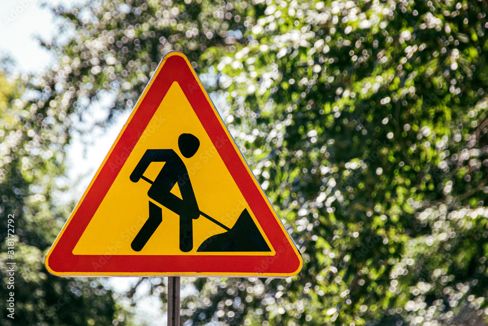 Roadworks ahead road sign on a summer city street against trees Roadworks ahead road sign on a summer city street against trees