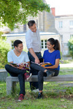 teacher talking to students sat on bench in campus