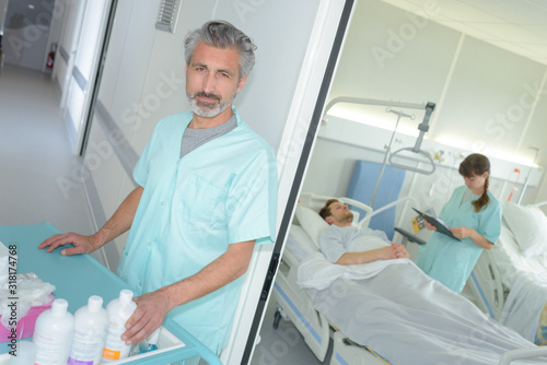 orderly with products on trolley nurse in room with patient