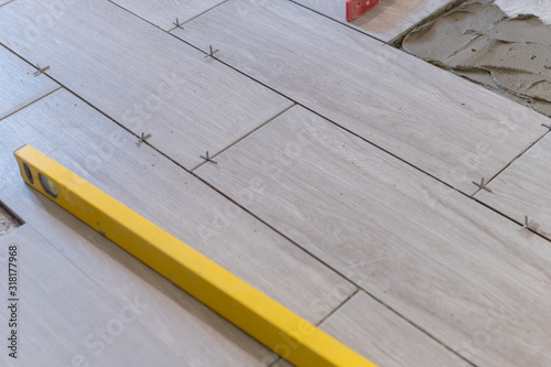 Close up shot of a metal yellow spirit level placed on a newly installed yet not finished kitchen tiles