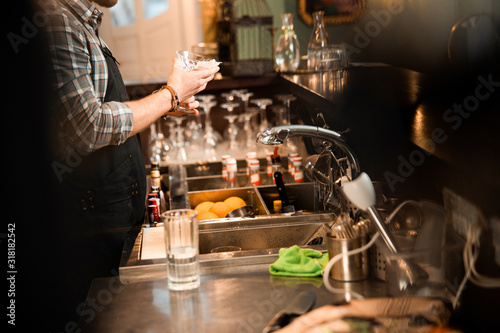 Professional young bartender is wiping a glass