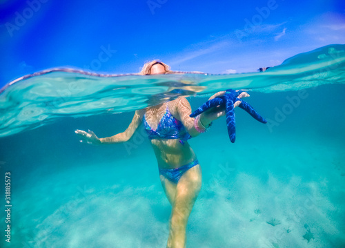 girl in tropical water holding a starfish in her hand, underwater photography
