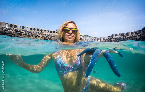 girl in tropical water holding a starfish in her hand, underwater photography