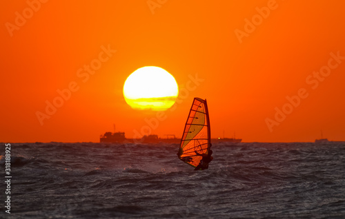 windsurf sail   in the rays of orange sunset