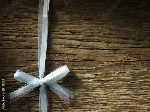 Decorative white ribbon and bow over wooden background