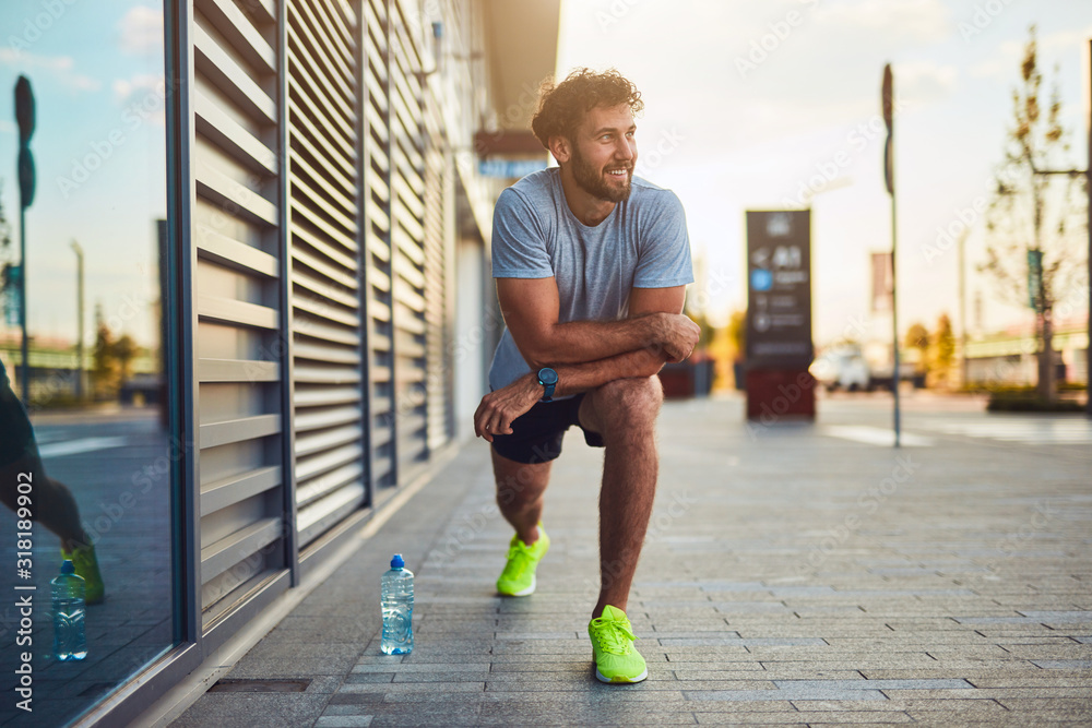 Young man exercising / stretching in urban area.