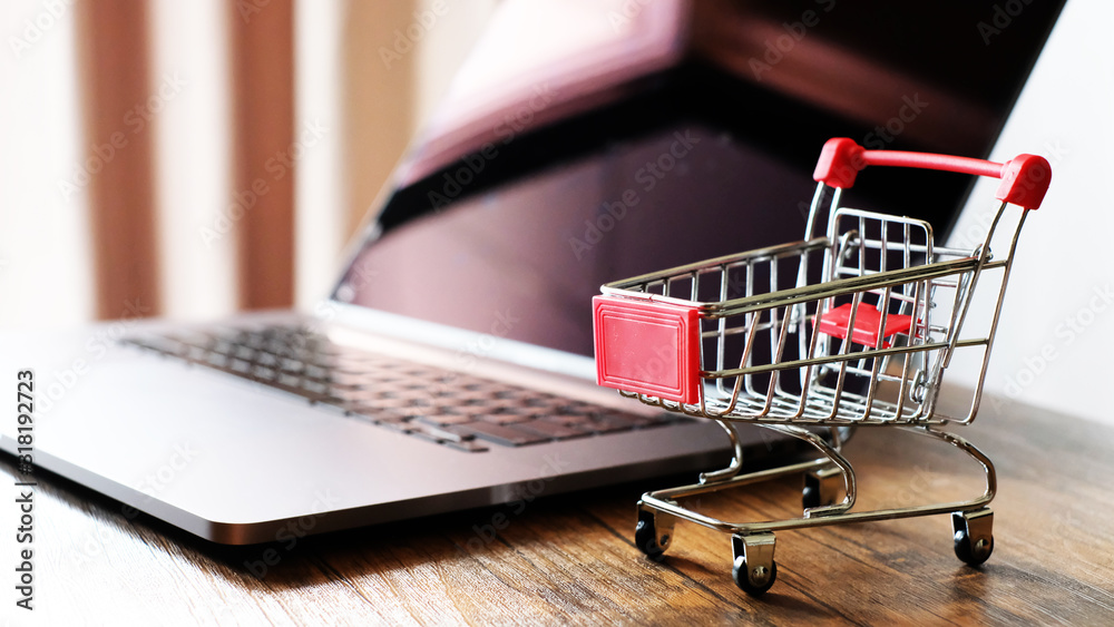 Shopping cart with laptop on the desk, online shopping concept.