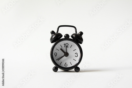 Black alarm clock on white background.