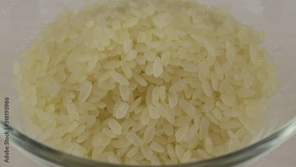 Grain rice falling in a transparent glass bowl Grain rice falling in a transparent glass bowl