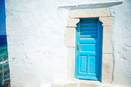 Traditional houses withe blue doors in the narrow streets of Mykonos, Greece. © travnikovstudio