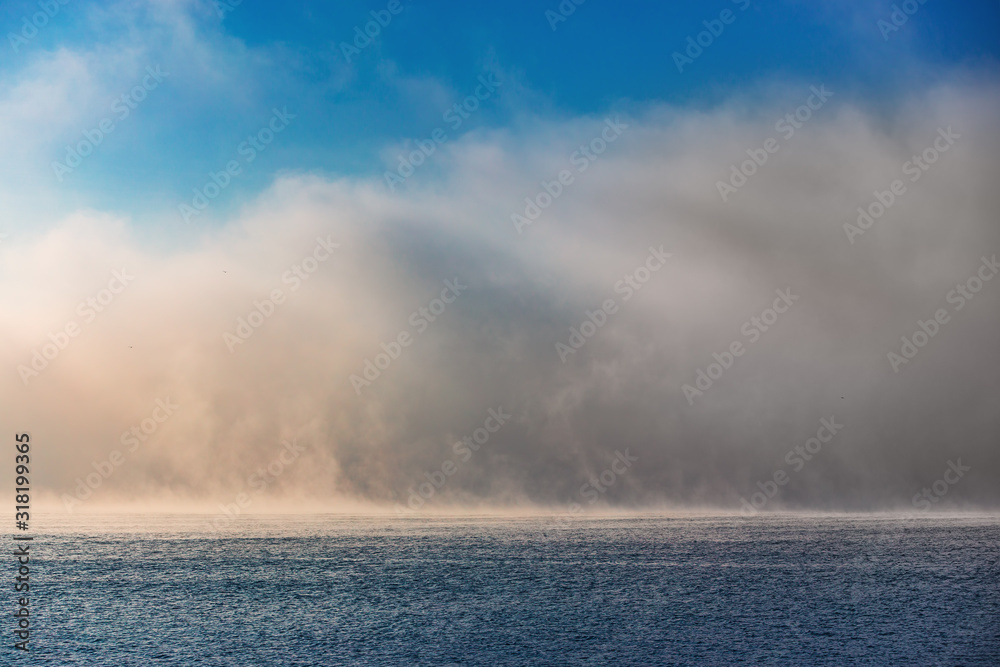 Sea sunrise and foggy morning. Fog above blue ripple water, aerial view