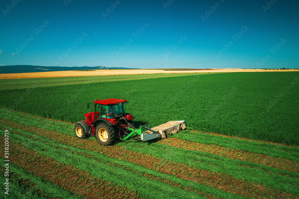 Fototapeta premium Tractor mowing green field