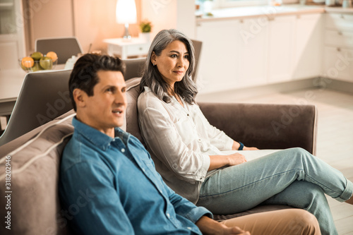Adult couple sitting on couch and looking away