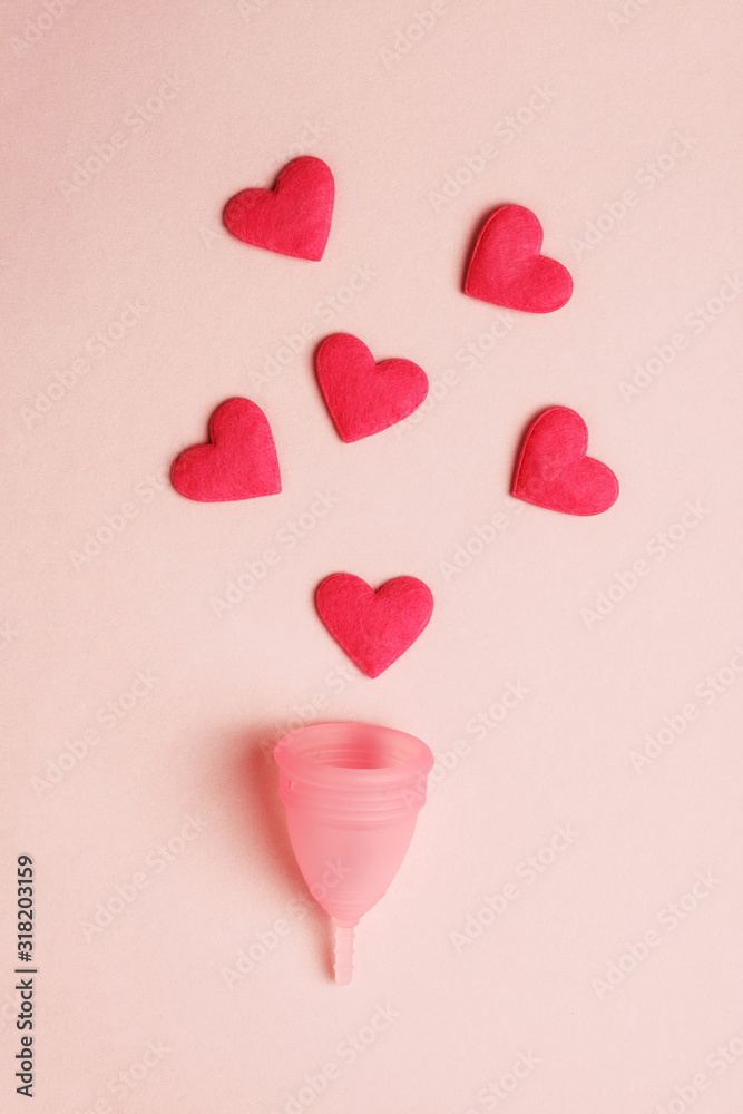 pink menstrual cup and red hearts as blood drops isolated on rose background,  menstruation cycle, women gynecological health and intimate hygiene concept, zero waste product