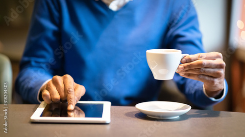 Black guy sitting in cafe drinking cup of tea