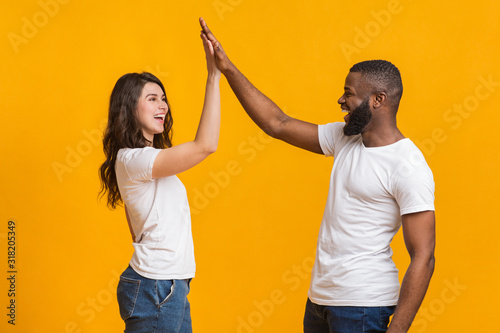 Bild auf Leinwand Joyful interracial sweethearts giving high-five to each other, clapping hands