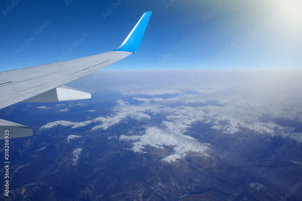 View of the wing of an airplane over the snowy mountains. Beautiful landscape.