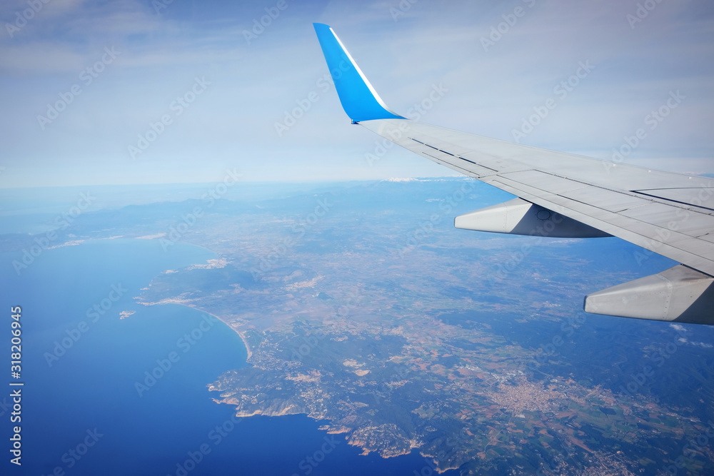 Window view of travel tourism airplane. The wing of an airplane flying over the sea.