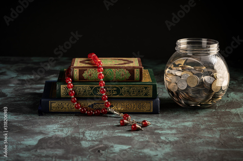 Zakat concept: Quran and tasbih with jar full of coins