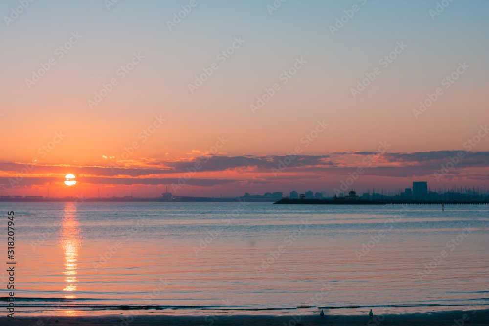 Sunset in a bay near the city. Bright colores. A silhouette of city centre. Asymmetrical composition