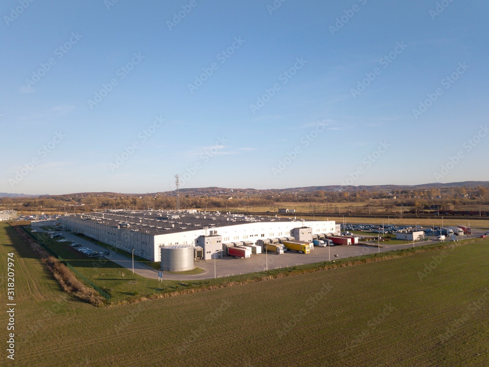 A bird's-eye view of a factory located among green fields. Aerial photography of an industrial facility from a drone or quadrocopter. Transportation of goods to the warehouses of the enterprise