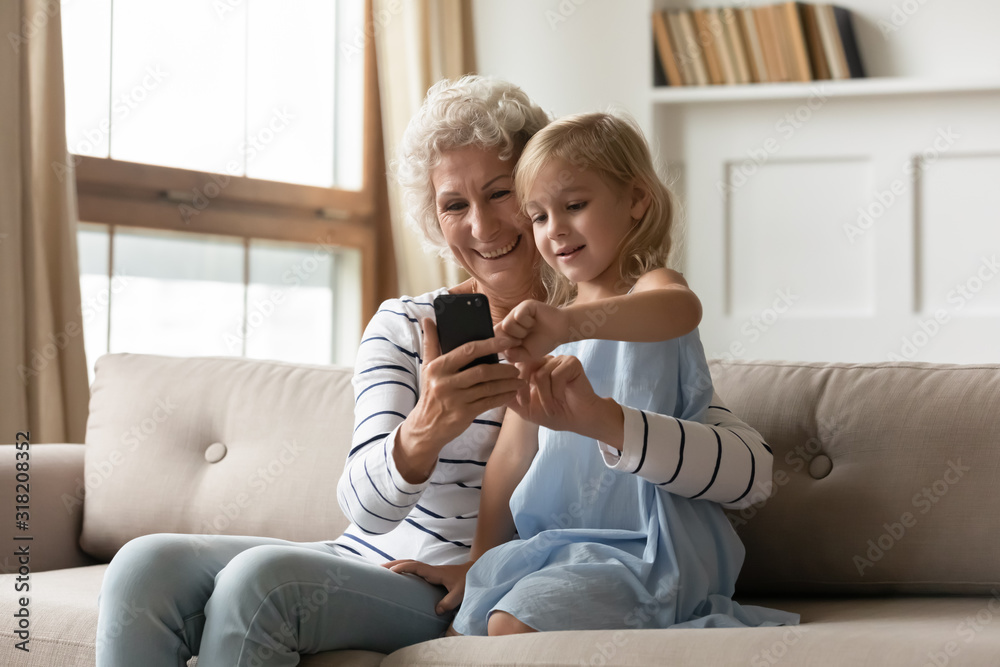 Middle aged woman using smartphone with adorable child girl. Middle aged woman using smartphone with adorable child girl.