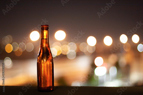 A full bottle of beer on a night city lights background