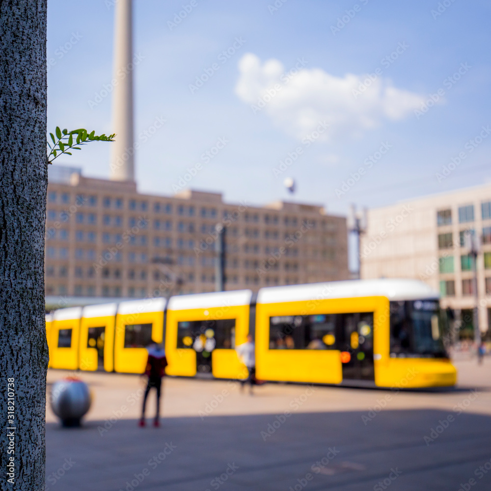 baum auf alexanderplatz in berlin im Fokus, unscharfe tram im hintergrund
