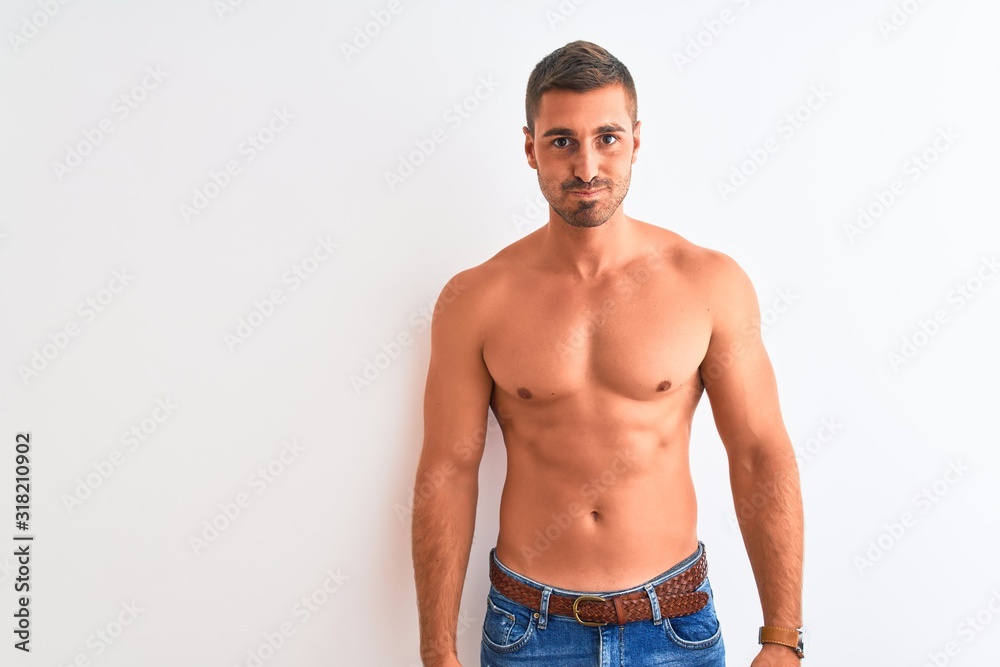Young handsome shirtless man showing muscular body over isolated background puffing cheeks with funny face. Mouth inflated with air, crazy expression.