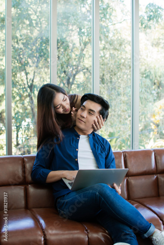 An asian couple is playing in laptop