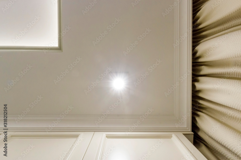 Illuminated ceiling corner bottom view - 2-tier ceiling and beige curtains. Illuminated ceiling corner bottom view - 2-tier ceiling and beige curtains.
