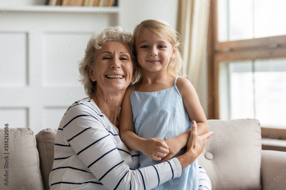 Pleasant middle aged woman cuddling small adorable grandchild. Pleasant middle aged woman cuddling small adorable grandchild.