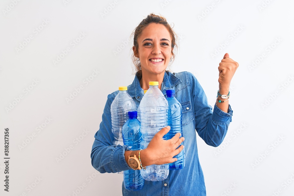 Young redhead woman holding plastic bottle to recycle over isolated background screaming proud and celebrating victory and success very excited, cheering emotion Young redhead woman holding plastic bottle to recycle over isolated background screaming proud and celebrating victory and success very excited, cheering emotion