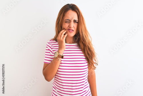 Young redhead woman wearing striped casual t-shirt stading over white isolated background touching mouth with hand with painful expression because of toothache or dental illness on teeth. Dentist