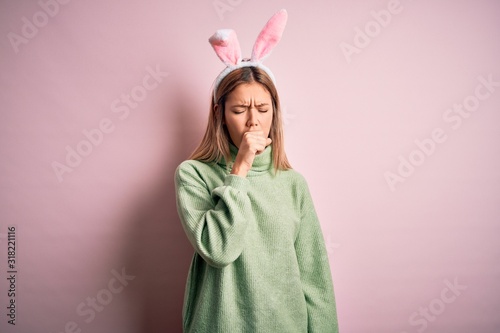 Young beautiful woman wearing easter rabbit ears standing over isolated pink background feeling unwell and coughing as symptom for cold or bronchitis. Health care concept.