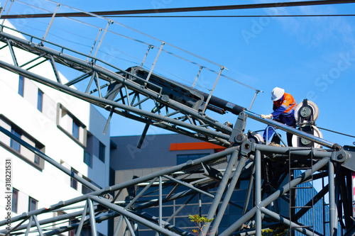 Melbourne, Australia - May 2 2018 - The worker adjusts the fasteners on the construction mobile crane on the sky background