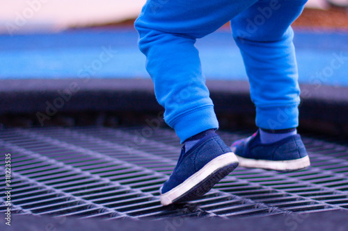 A boy on the playground jumping on a trampoline. A view of legs hovering in the air.