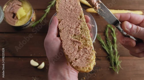 Cook spreading tasty poultry pate on French baguette or bread with a knife