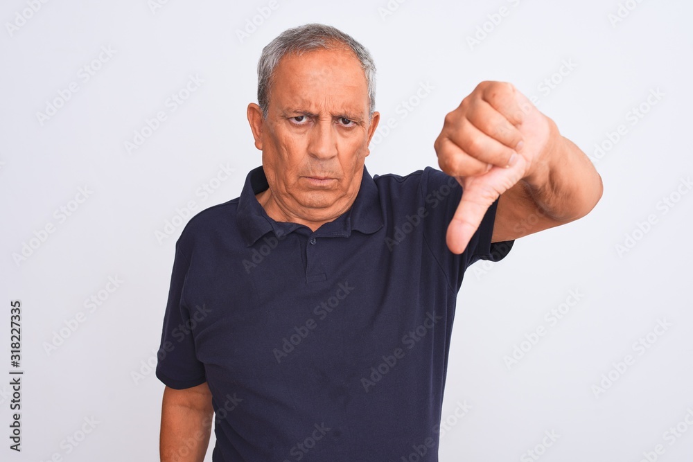 Senior grey-haired man wearing black casual polo standing over isolated white background looking unhappy and angry showing rejection and negative with thumbs down gesture. Bad expression. Senior grey-haired man wearing black casual polo standing over isolated white background looking unhappy and angry showing rejection and negative with thumbs down gesture. Bad expression.