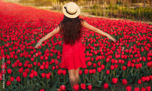 Young woman standing on red tulips field enjoying freedom