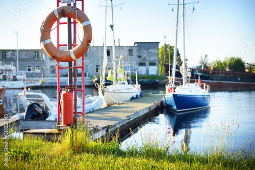 A view of a small yacht marina on a sunny summer day. Lifebuoy and fire extinguisher close-up. Port of Mersrags, Latvia photo