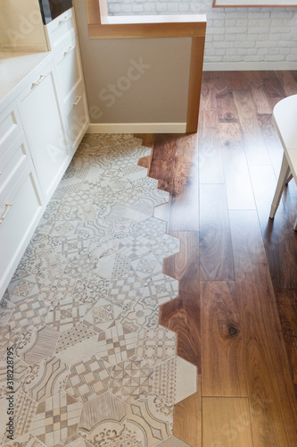 Fashionable mix of tile and parquet in the kitchen. Curved joint of ceramic tiles and wooden floor