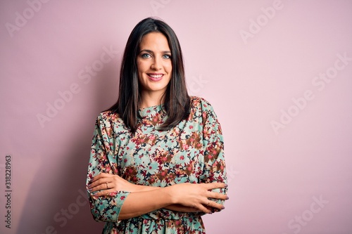 Photography Young brunette woman with blue eyes wearing floral colorful dress over pink background happy face smiling with crossed arms looking at the camera