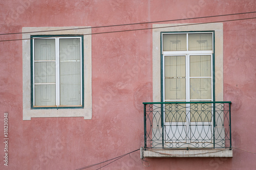 Typical window and balcony with pink buildng exterior facade, in Lisbon Portugal photo