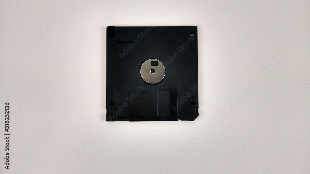 Black disk - Diskette behind white background Black disk - Diskette behind white background