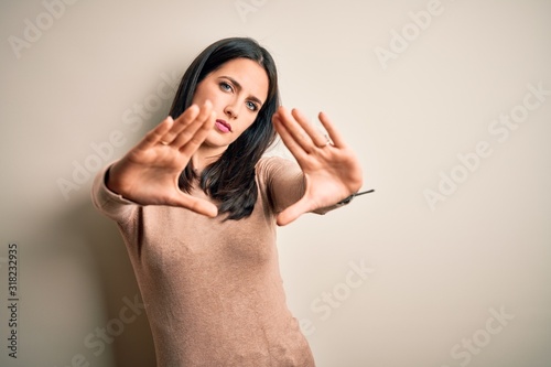 Young brunette woman with blue eyes wearing casual sweater over isolated white background doing frame using hands palms and fingers, camera perspective