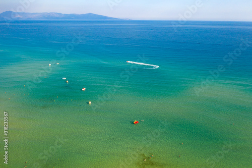 Drone view of sailing boats in deep blue clear water.